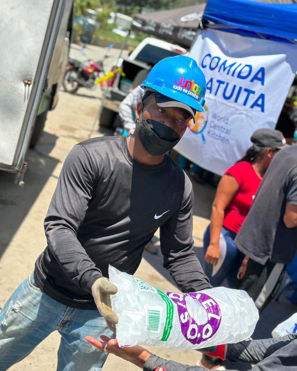 Hombre recibiendo agua gratuita junto a una carpa de World Central Kitchen