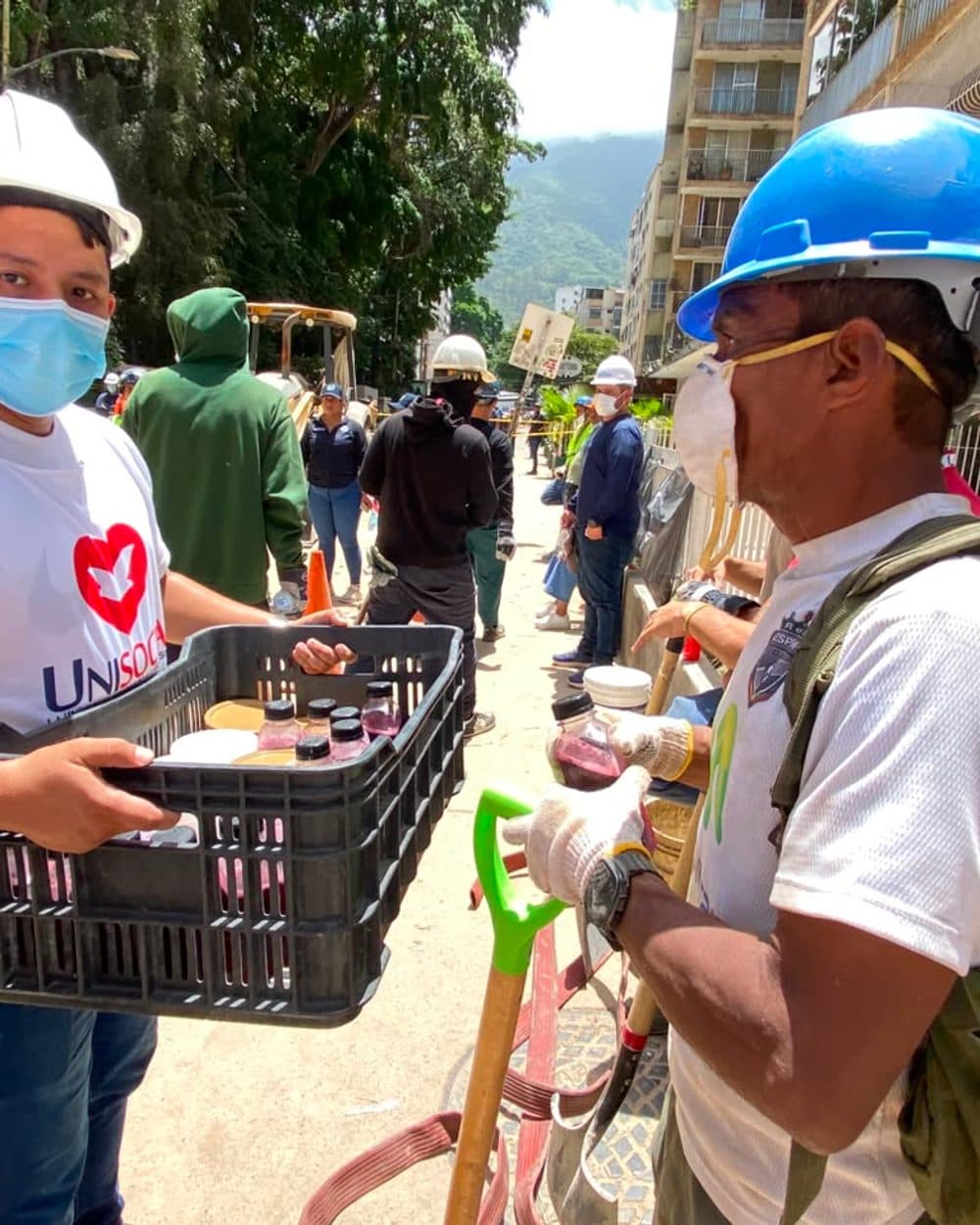 Voluntario entregando agua a un trabajador de rescate
