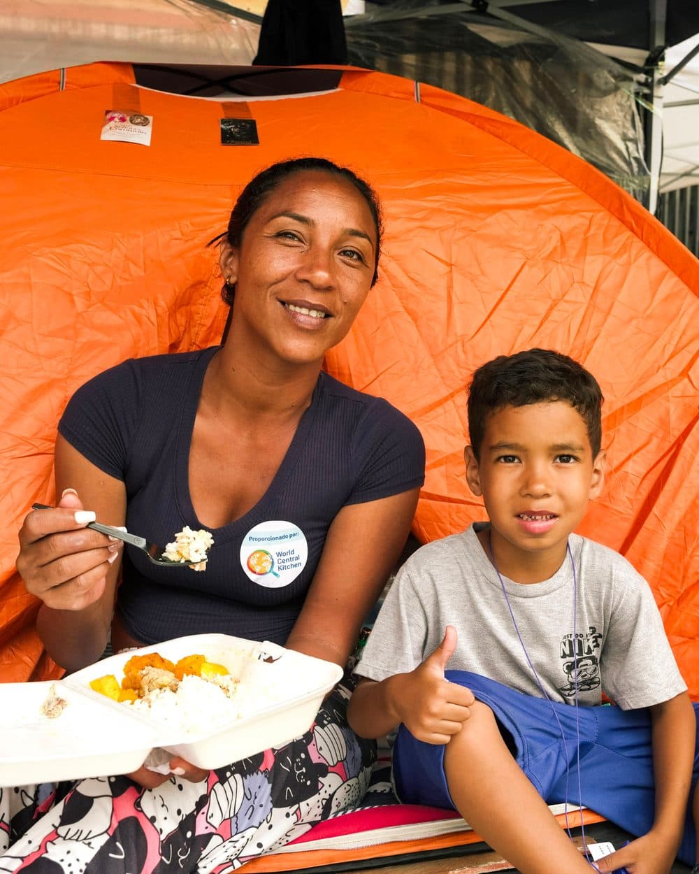 Madre e hijo comiendo una comida de World Central Kitchen