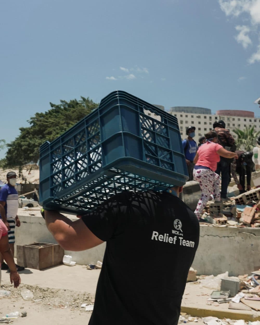 Voluntario del Relief Team cargando una caja de comida entre los escombros